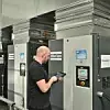 Mitarbeiter steht vor einem Druckluftkompressor von Atlas Copco und nimmt Einstellungen vor.