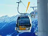 Auf dem Bild ist eine Seilbahnkabine im Alpenpanorama zu sehen.