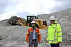 Zwei Personen in Schutzkleidung vor einem Radlader in einem Steinbruch