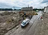 Weitwinkelansicht einer Großbaustelle mit Baggern, Lkw und Arbeitergruppe