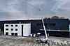 Mobiler Kran auf Betonfläche vor zweifarbiger Industriehalle im Außenbereich